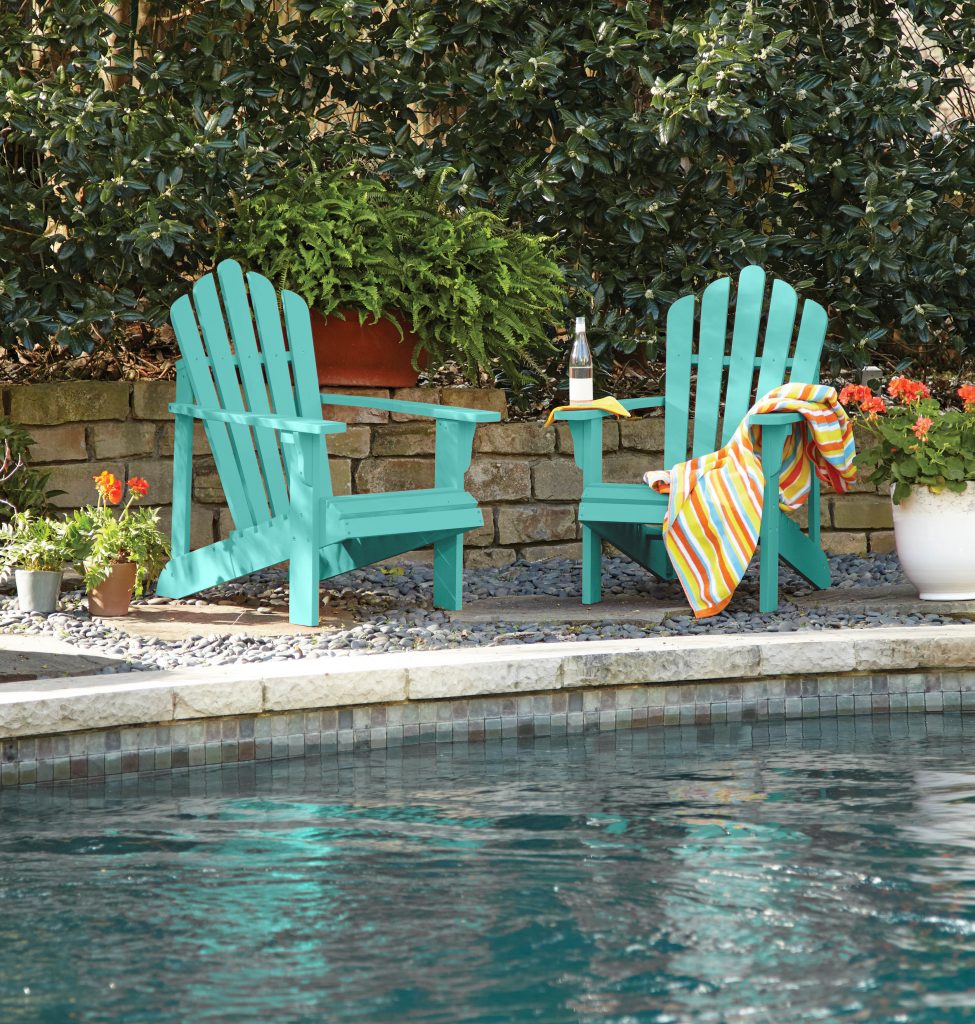 Adirondack chairs painted in a teal color and pool in the foreground.
