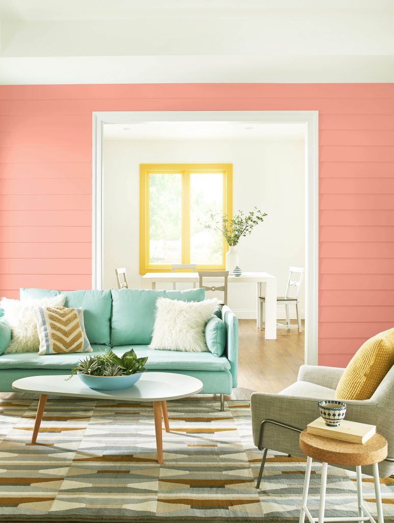 Interior living room in foreground with dining area in background. Coastal vibe colors in peach, teals and yellows.