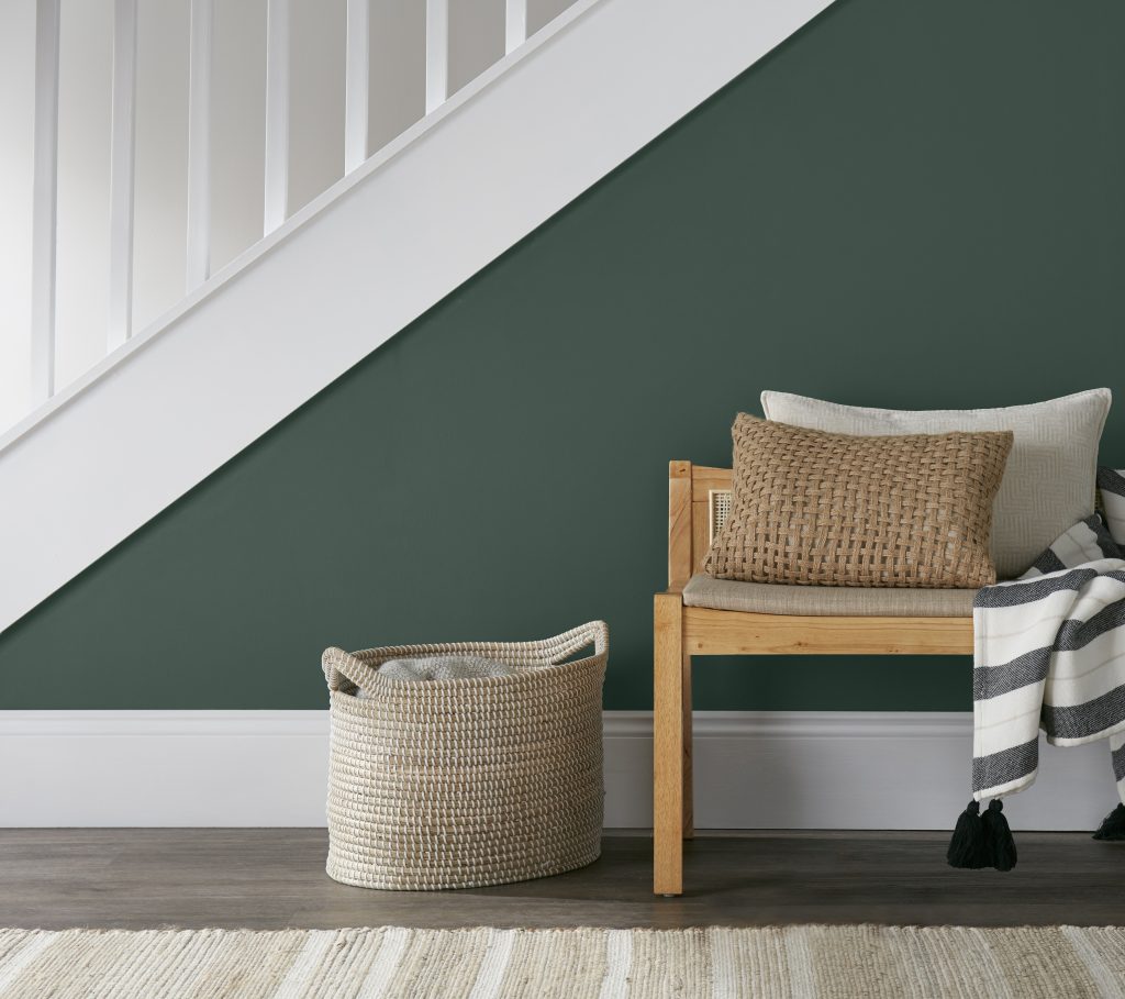 Staircase wall used as an accent in a green hue with a seat in front.