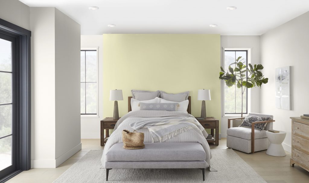 A California modern style bedroom with two large windows and French door leading outside.  The color on the walls is a white tone called Blank Canvas and the accent color behind the bed is a yellow-green called Hybrid. 