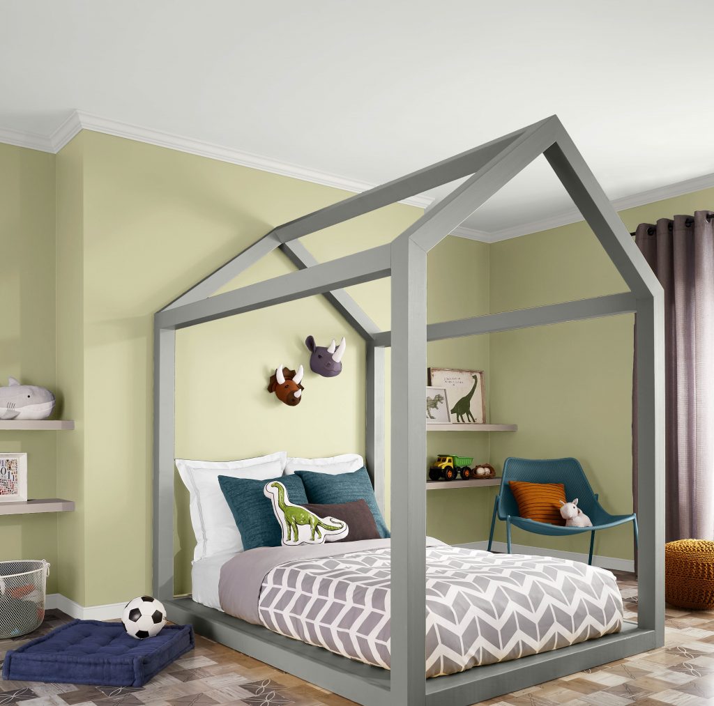 A large kids rooms featuring a custom bed and frame shaped as a "house". 
The color on the walls creates a soothing atmosphere and the pops of color used throughout the room provide a playful touch to this room. 