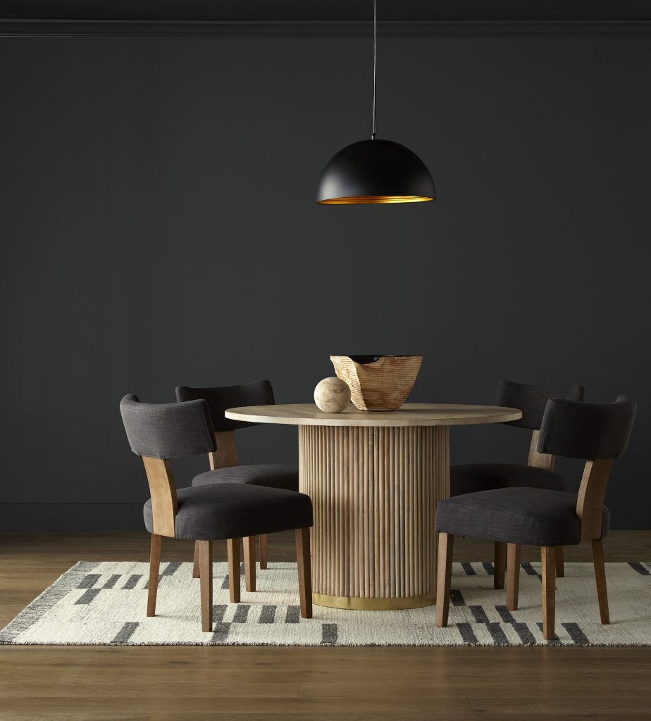 A modern black color dining room setting featuring a circular wood table, contemporary wood and upholstered chairs with minimalistic organic shaped accessories.  