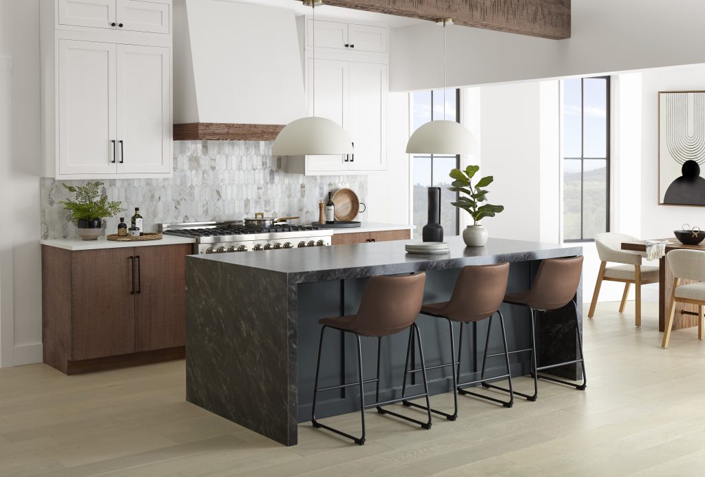  A large open kitchen and dining room space, the design style is soft modern  with some modern rustic elements. The walls are painted in a popular white color called Weathered White and BEHR's 2024 color of the year, Cracked Pepper is being used on the kitchen island as an accent. 