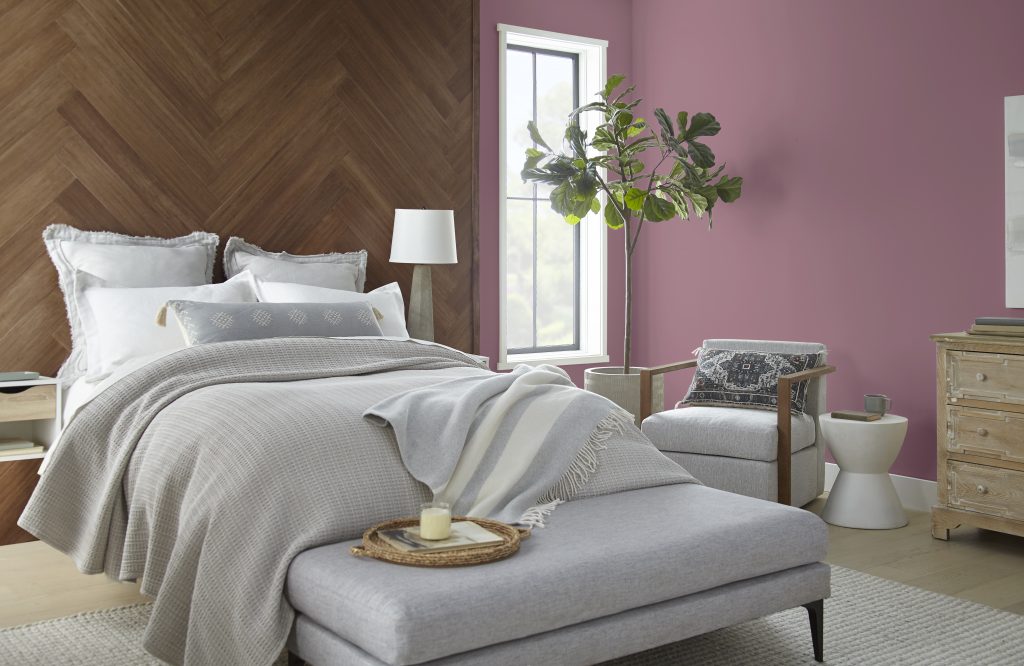 Bedroom with a large wood headboard. The walls in the room are painted in a pinkish-purple color.