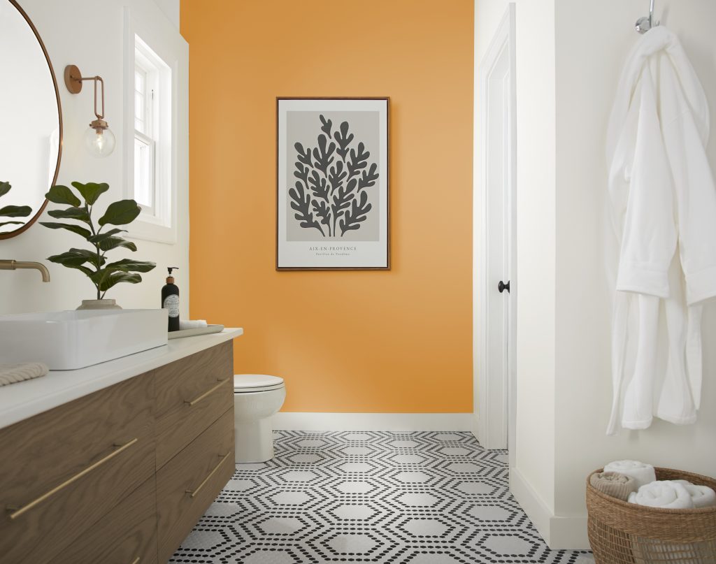 A modern farmhouse bathroom with a cheerful yellow accent wall.  The floor features a black and white and eye-catching geographic design. 