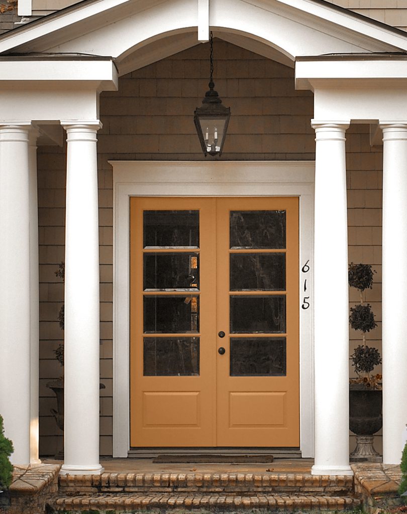 An entryway showing a door painted in a golden orangy-yellow hue.