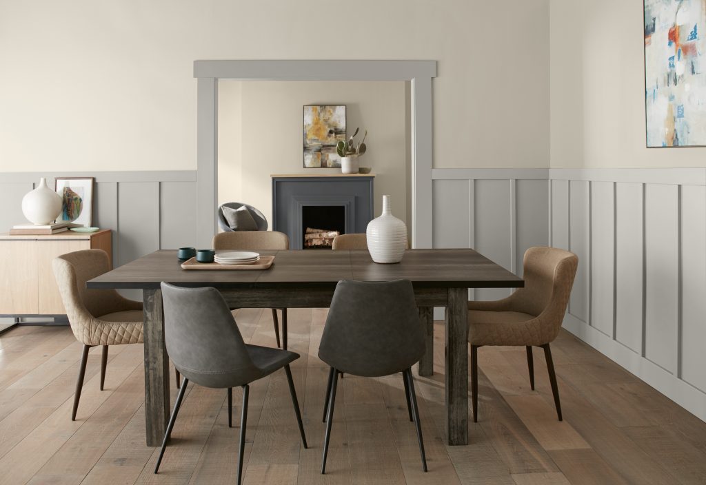 A modern farmhouse style dining and living room space.  The colors on the walls range from warm to cool neutral tones, including Cracked Pepper, a soft black used on the fireplace. 