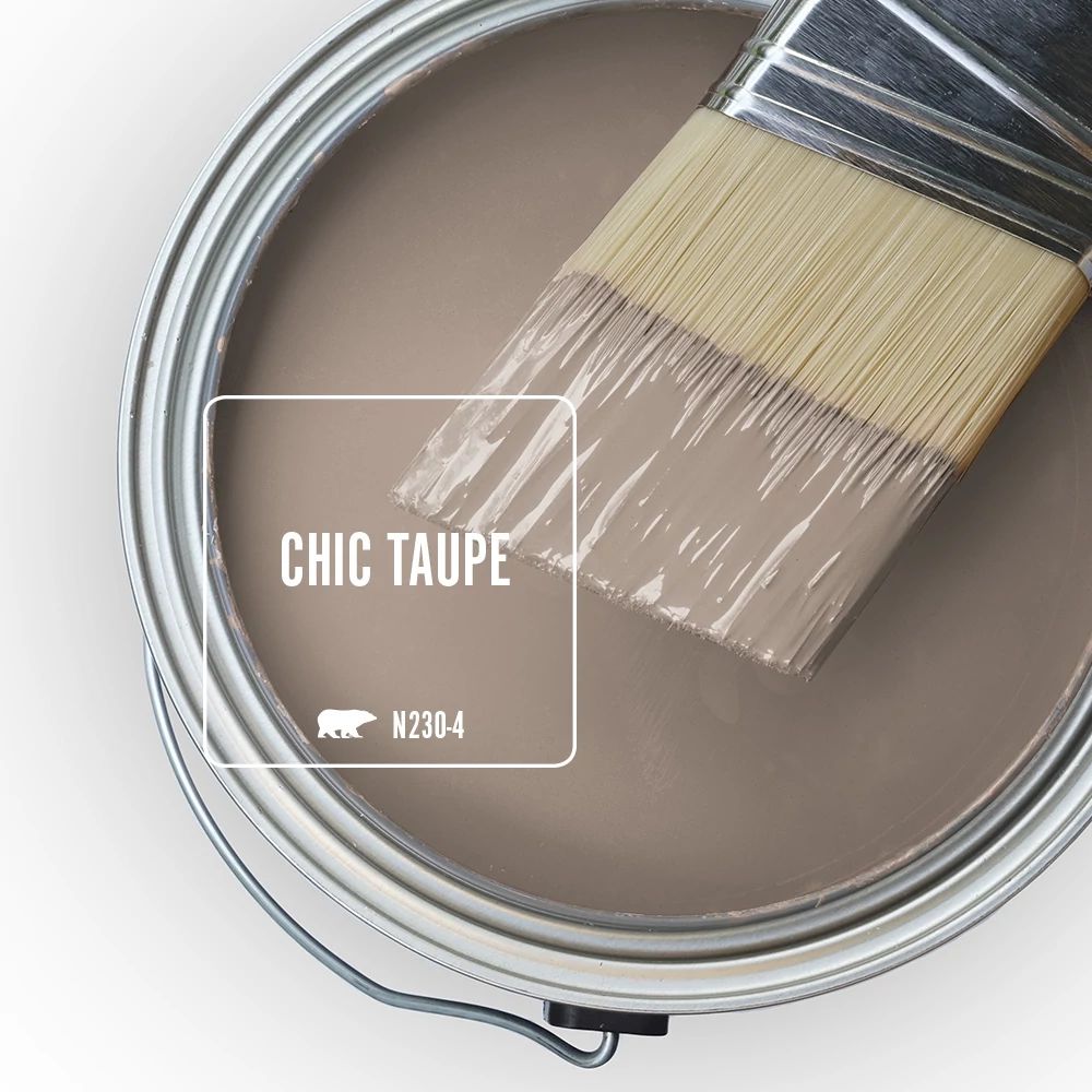 An open paint call with a half dipped paint brush on top of it, the featured color is Chic Taupe. 