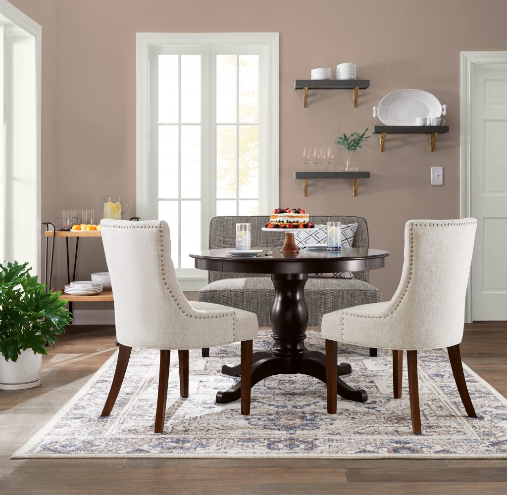 An inviting dining room with medium  neutral walls and white trim and baseboards. The seating furniture is upholstered with other neutral variation which provide depth and a refined look. 