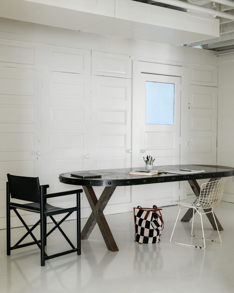 An office area in the basement with white walls and a dark brown table.