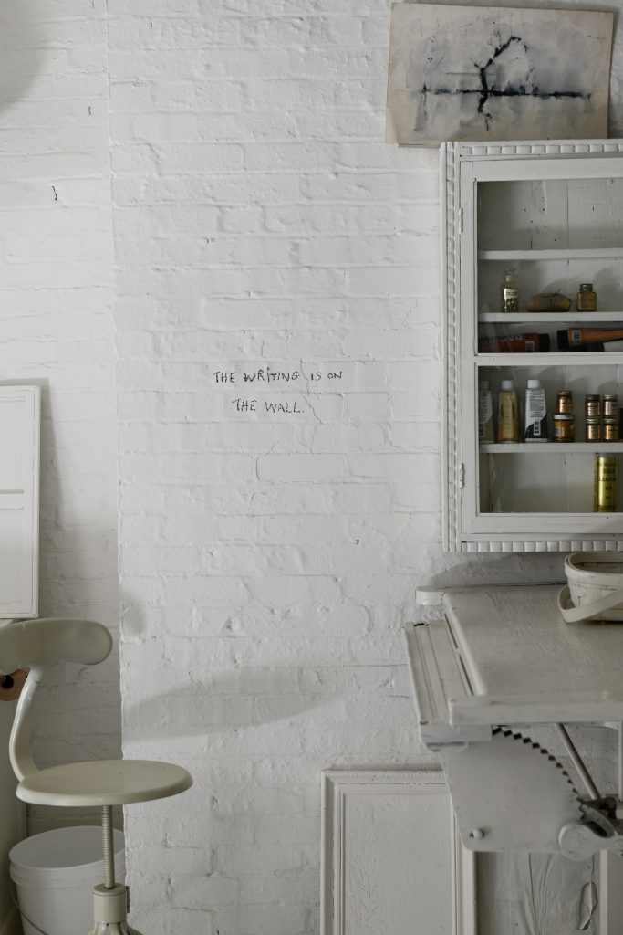 A painted brick wall in the basement with the words written on it; "The writing is on the wall".