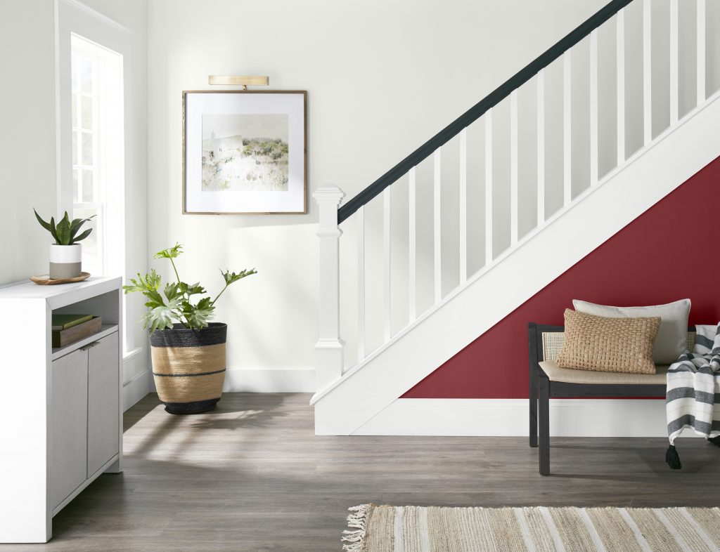 A room with all white walls and a small splash of red along the stairway wall.