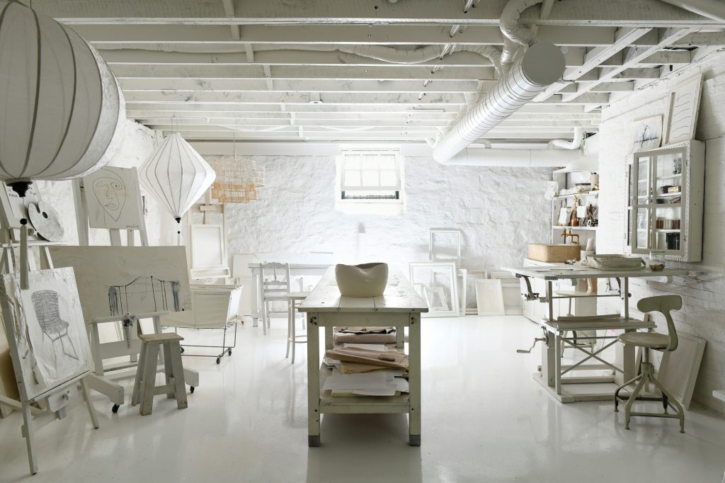 A workroom in the basement with all white walls and white furniture.