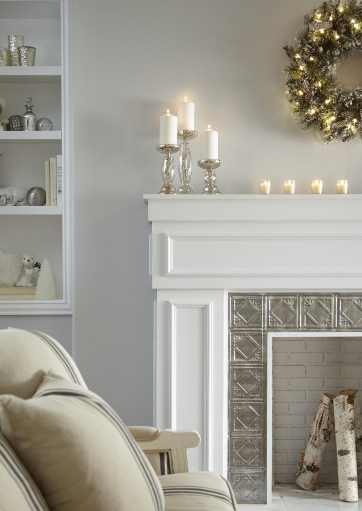 a corner of a fireplace showing lit candles on the mantle.
