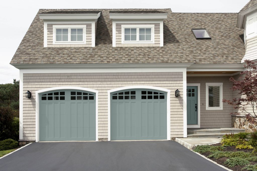 A home exterior with blue front and double garage doors. 