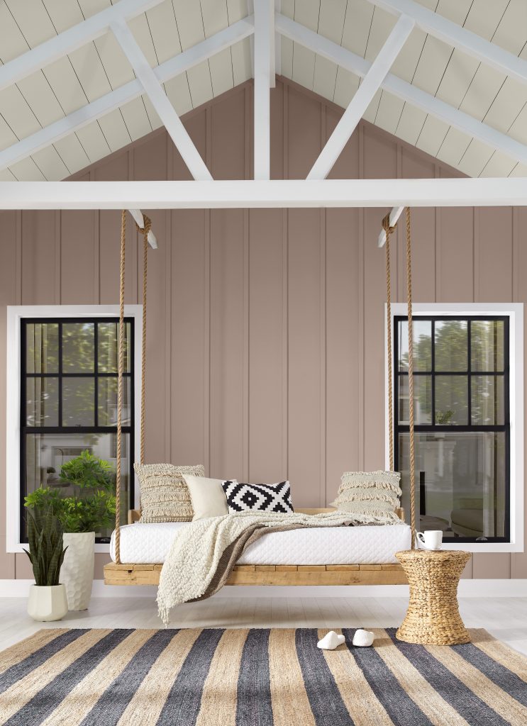 An exterior home painted in a warm cocoa hue with a cozy swing.