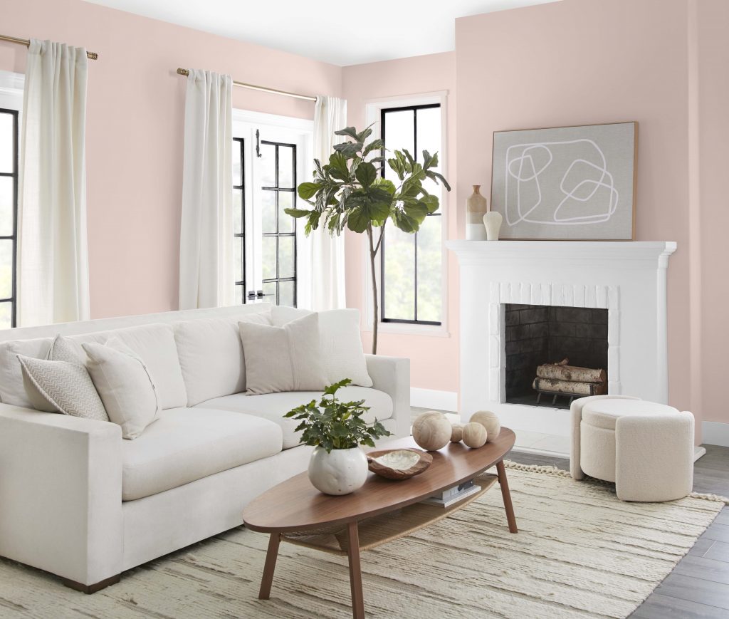 A casual living room with pink walls and white fireplace mantle and trim. 