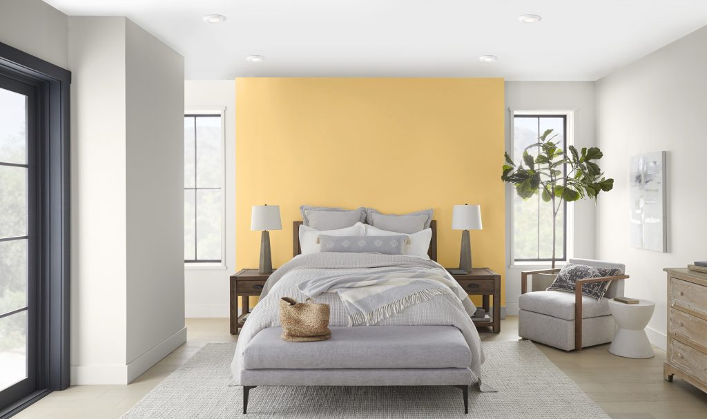 a bedroom painted in a creamy white with a backdrop of a wall painted in a yellow hue.