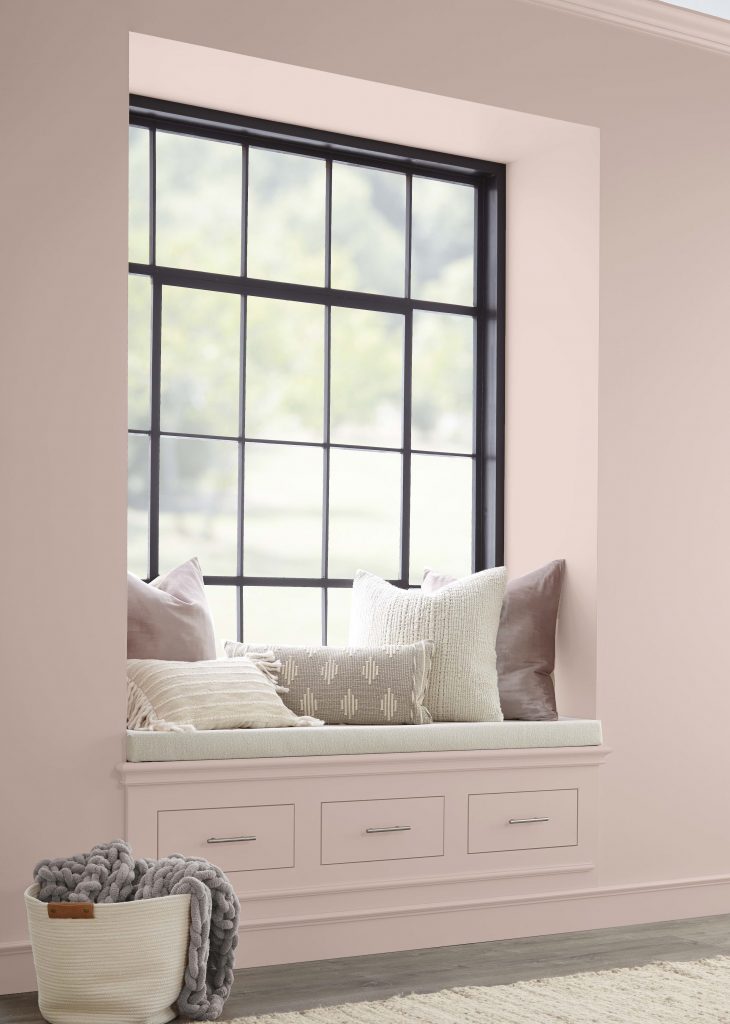 A reading nook surrounded with pink walls and pink decorative pillows. 