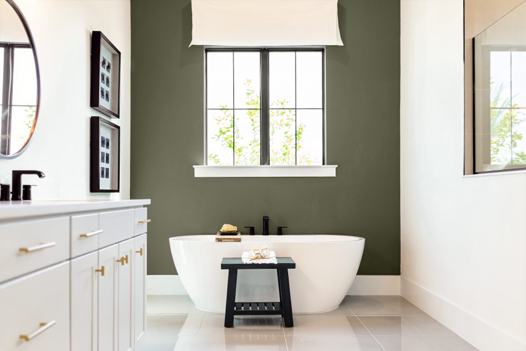 Bathtub in bathroom, the style is  modern luxe, the cabinet is white.  The mirror and sink hardware are oil-rubbed bronze and the door and drawer pull are metallic gold. 