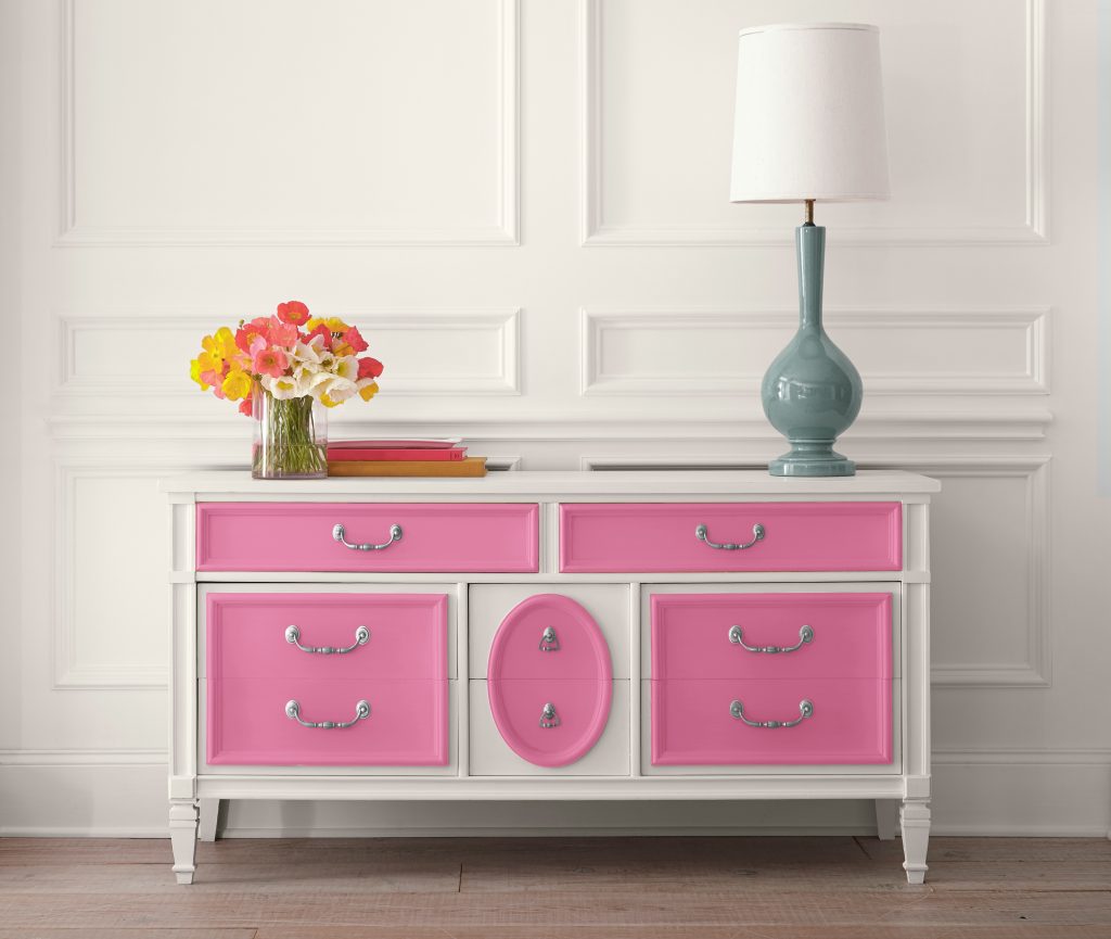 A white wall with a dresser against the wall paint in white with bright pink doors.