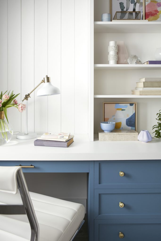 A small home office with a blue desk, the color on the wall and upper open shelves is Whipped Cream. 