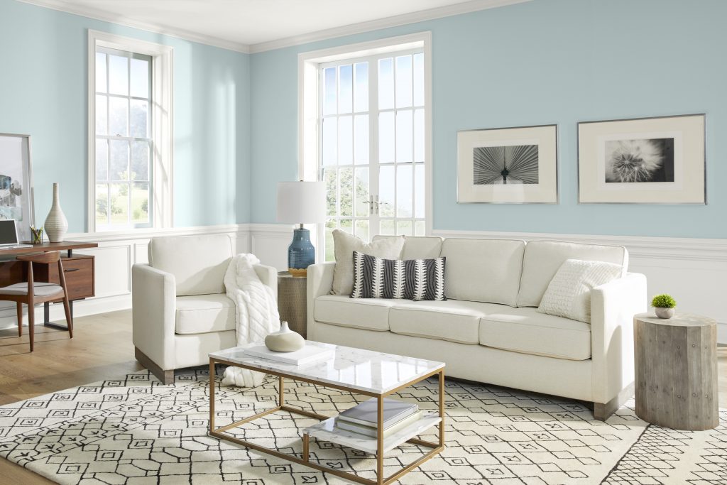A coastal style living room with light blue walls. The furniture is light and clean. 