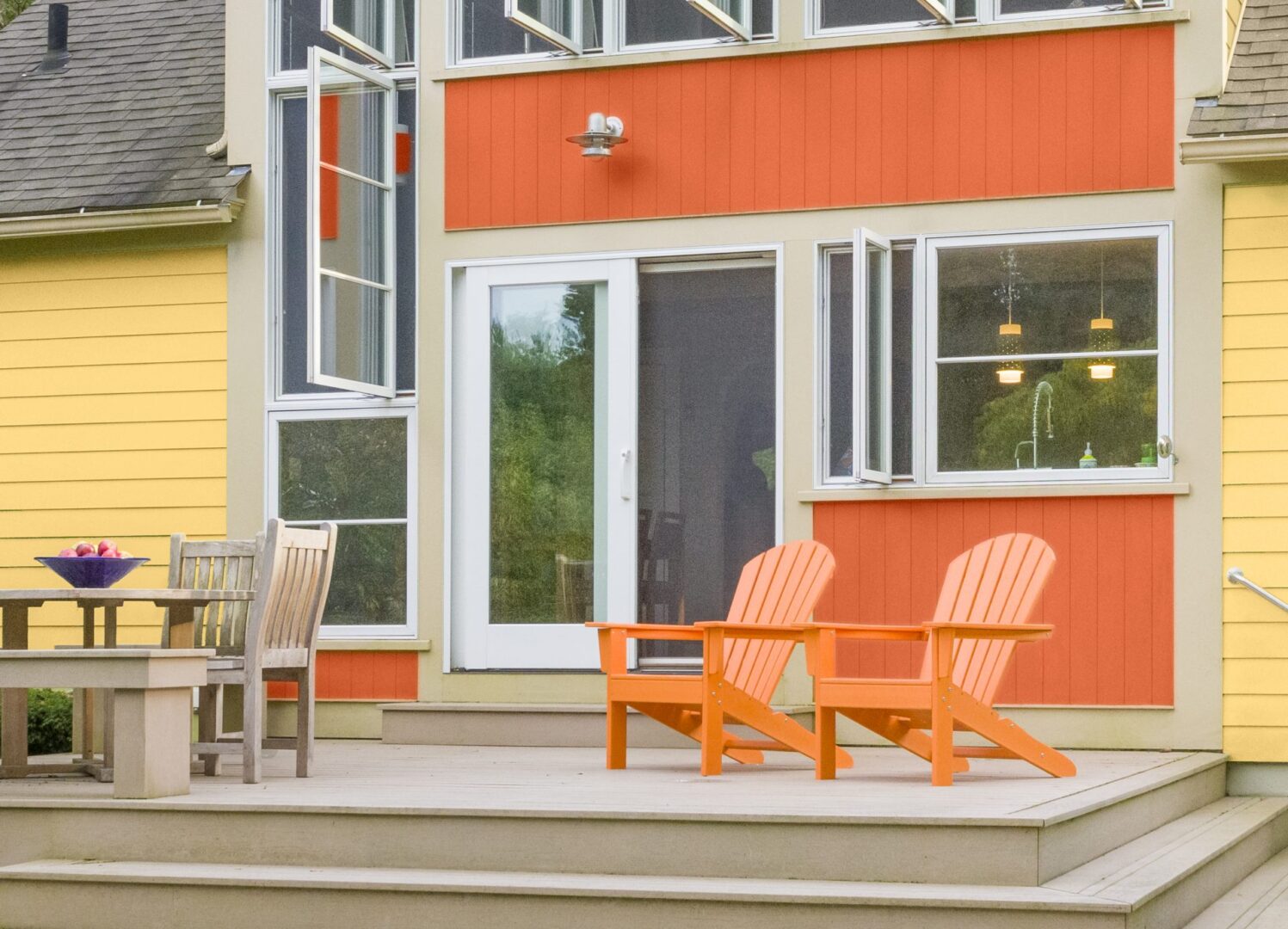A sitting area outside a home with bright orange painted walls.
