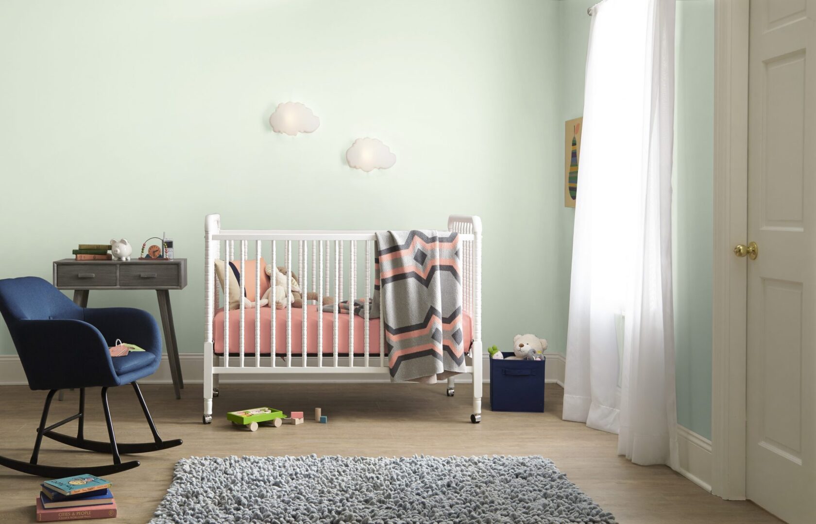 A nursery with walls painted in a soothing light green color.