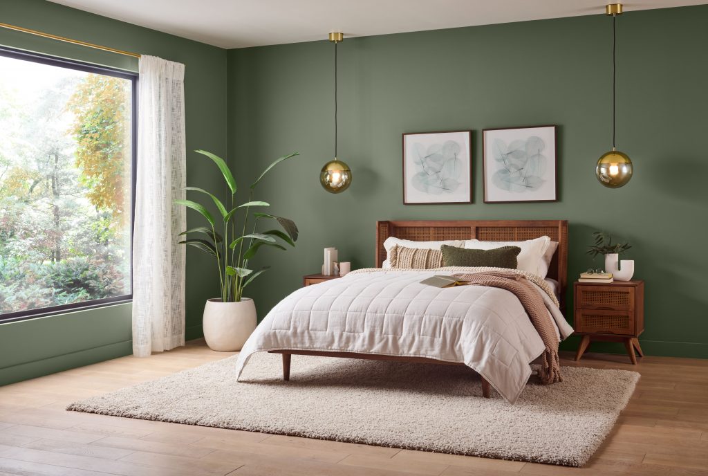 A bedroom with walls painted in a deep green hue.