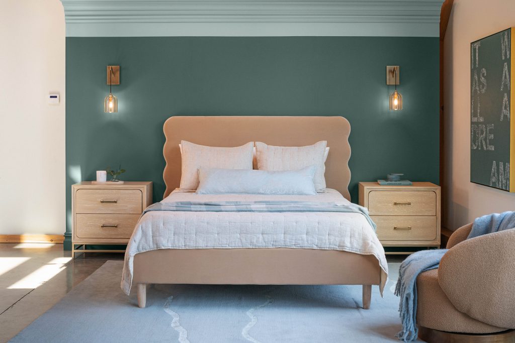 A bedroom painted in a deep jade hue with an accent of a sky blue for the molding.