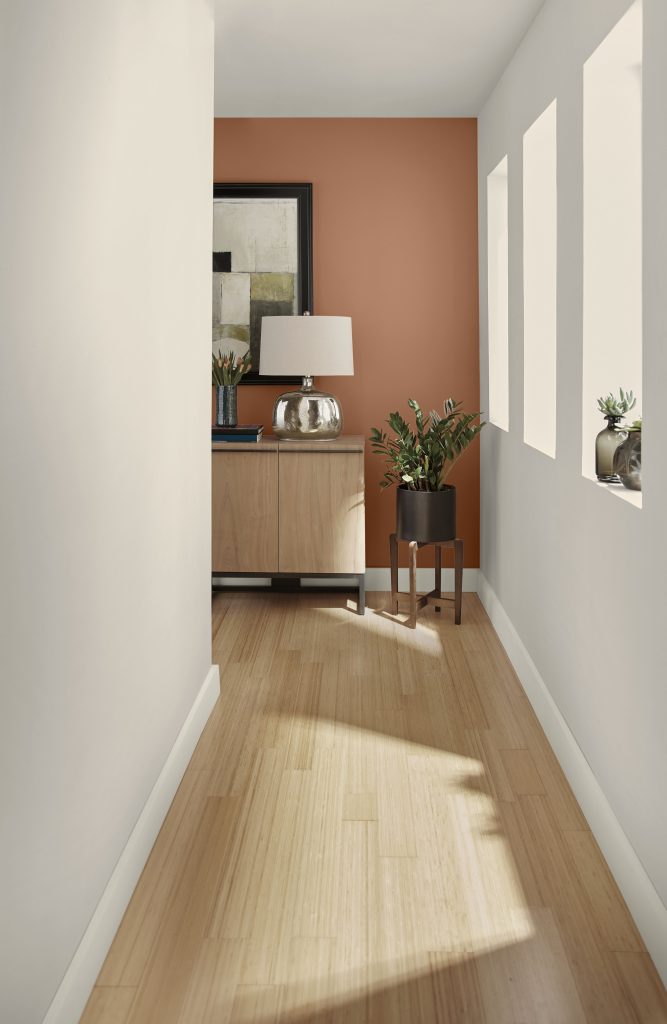 A hallway with walls in soft taupe leading to another wall painted in caramel orange.