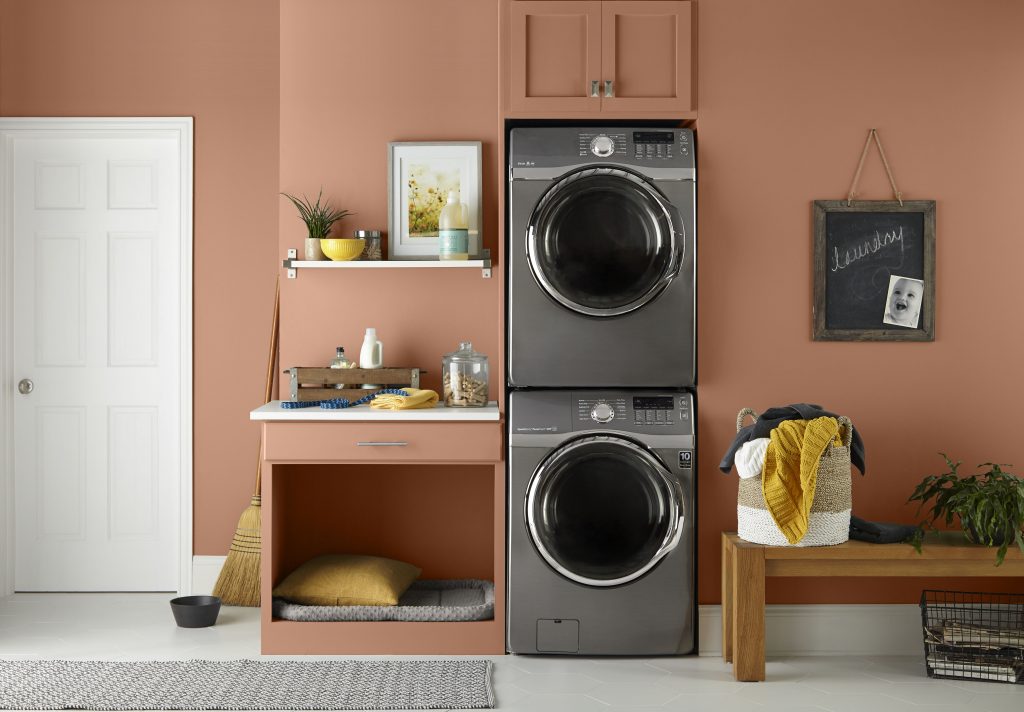 A laundry room with walls painted in a caramel orange hue.