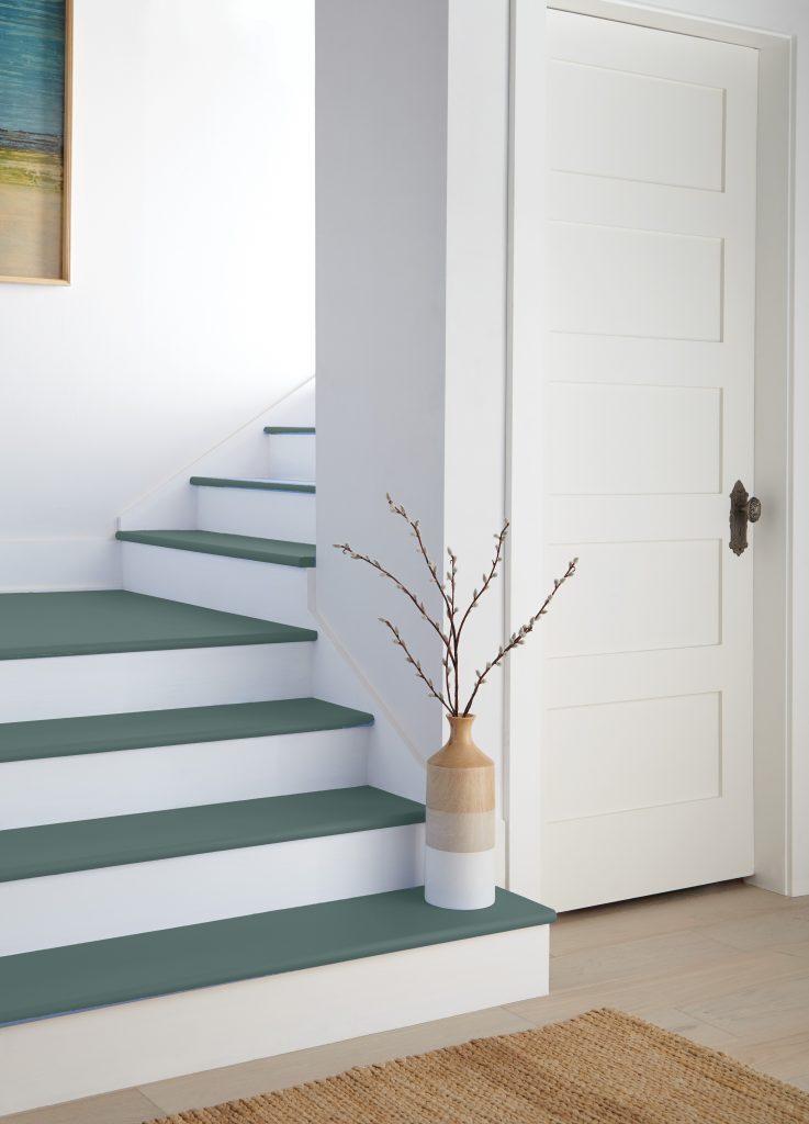 Modern interior with white risers and teal-painted stair treads, white paneled door, and a woven rug.