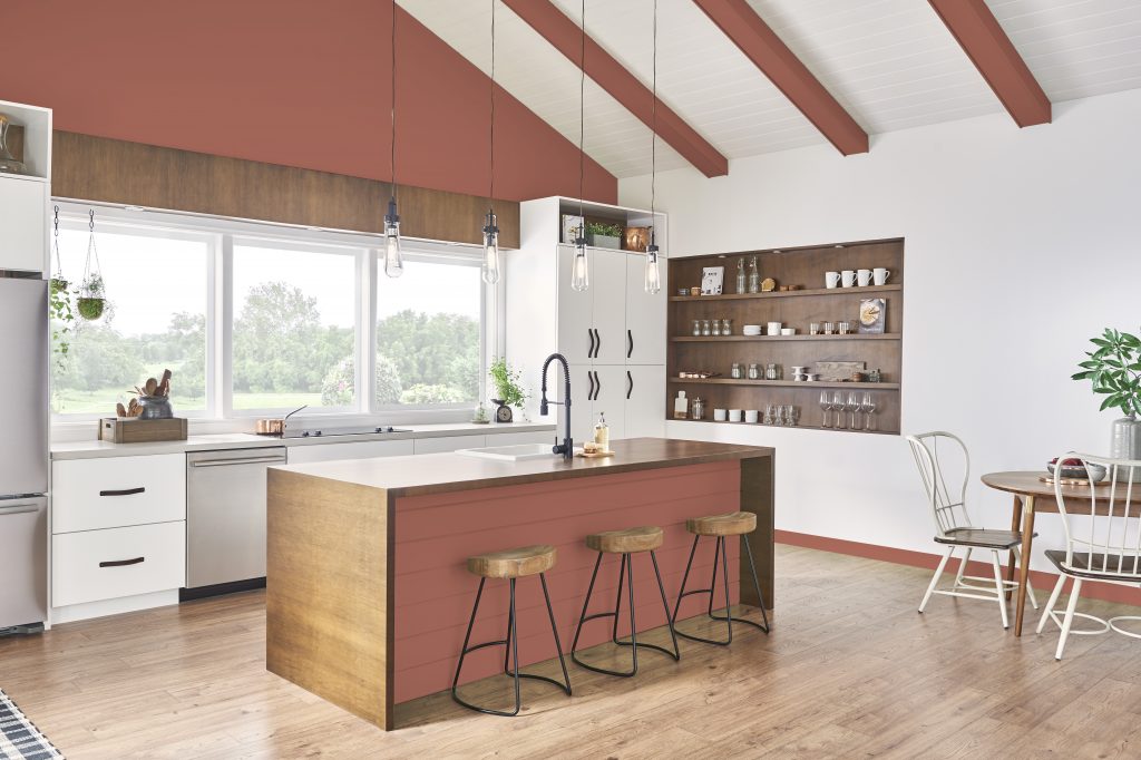 Modern kitchen with white walls, terracotta-painted ceiling beams and island front, wooden stools, and open shelving.
