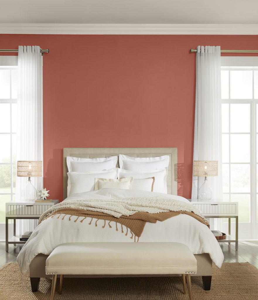 A bedroom with two windows and an upholstered bed and a bench.