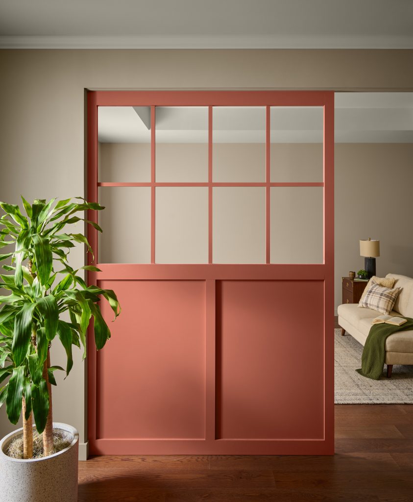 A room with a terra cotta color partition and a plant.