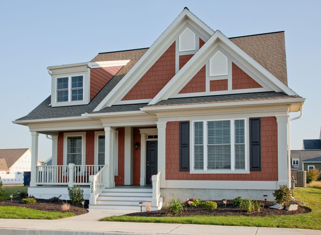 A traditional-style house with terra cotta color  siding, white trim, and black shutters, blending classic architecture with warm tones.