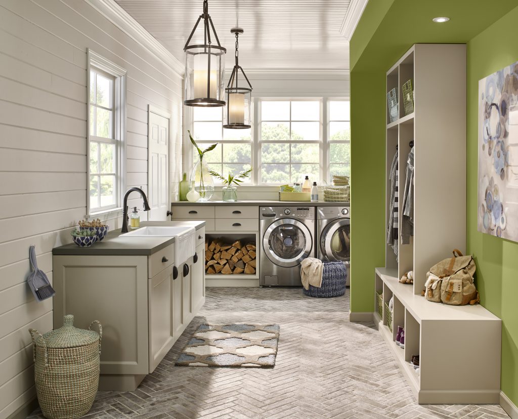A laundry room and entryway of a home with walls painted in neutral hues, except for one wall that is painted in an earthy green color.