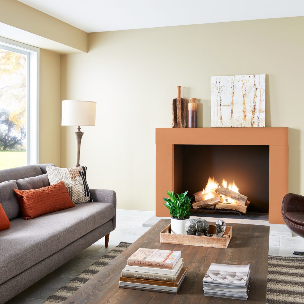 A living room with creamy white walls and a fireplace painted in a bright orange color.