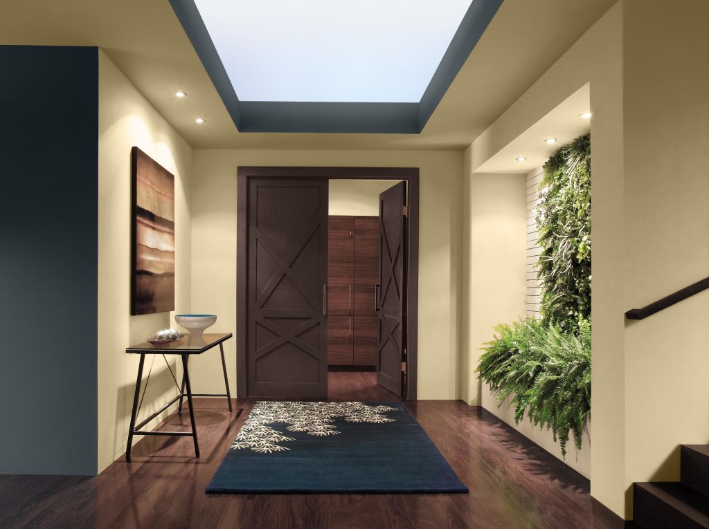 An entryway with a warm glowing yellow hue on the walls framed with an accent color in a blended blue-black.