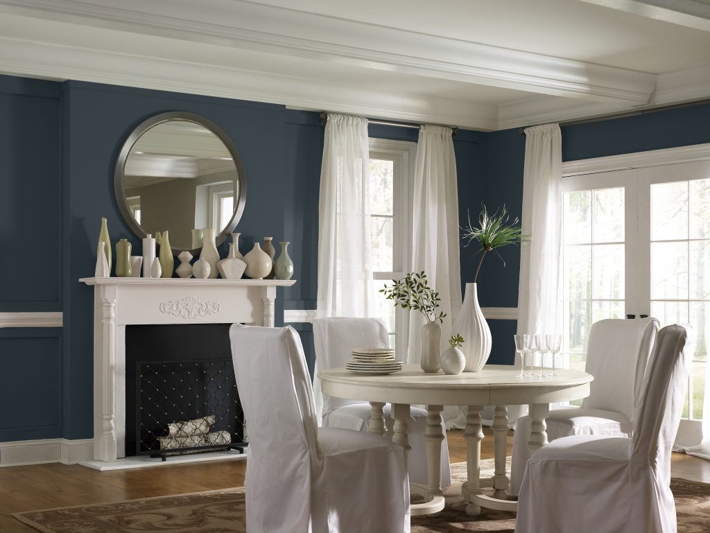 A dining room with a calming blue-black tone on the walls and a fireplace painted in a crisp white.