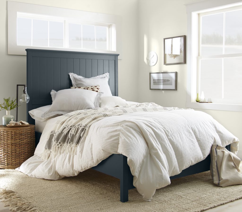 A bedroom with walls in soft white and headboard in a blended blue-black.