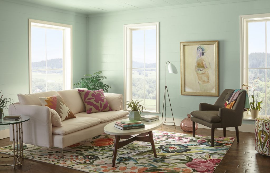 A garden living room with flowery decor and walls painted in a pastel green.