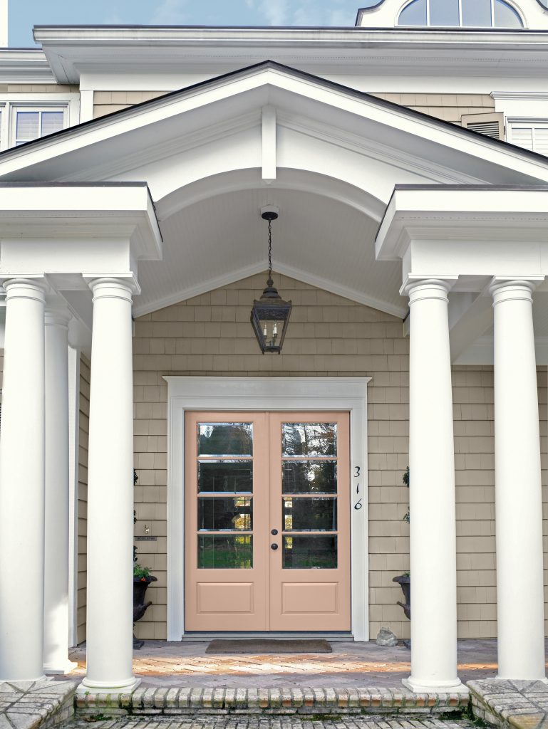 A traditional home entrance with siding painted Smoked Tan, bright ULTRA PURE WHITE® trim, and double front doors in Iced Copper, framed by tall white columns, a covered portico, and a classic hanging lantern above the entry.