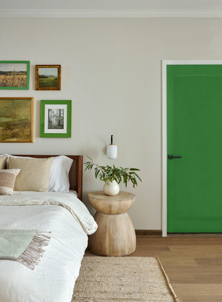 Bedroom with a muted green accent door, warm wood floors, and crisp white bedding