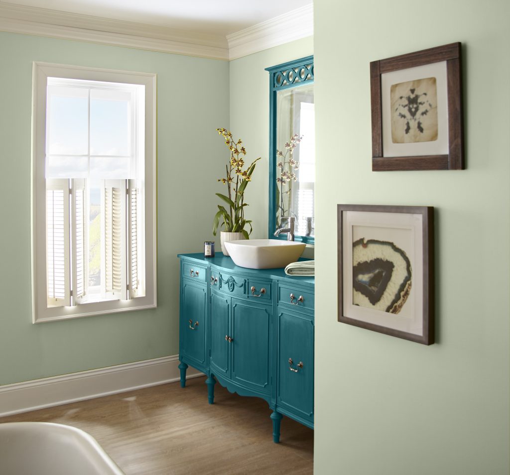 Light-filled bathroom with soft sage green walls creating a calm, spa-like feel.