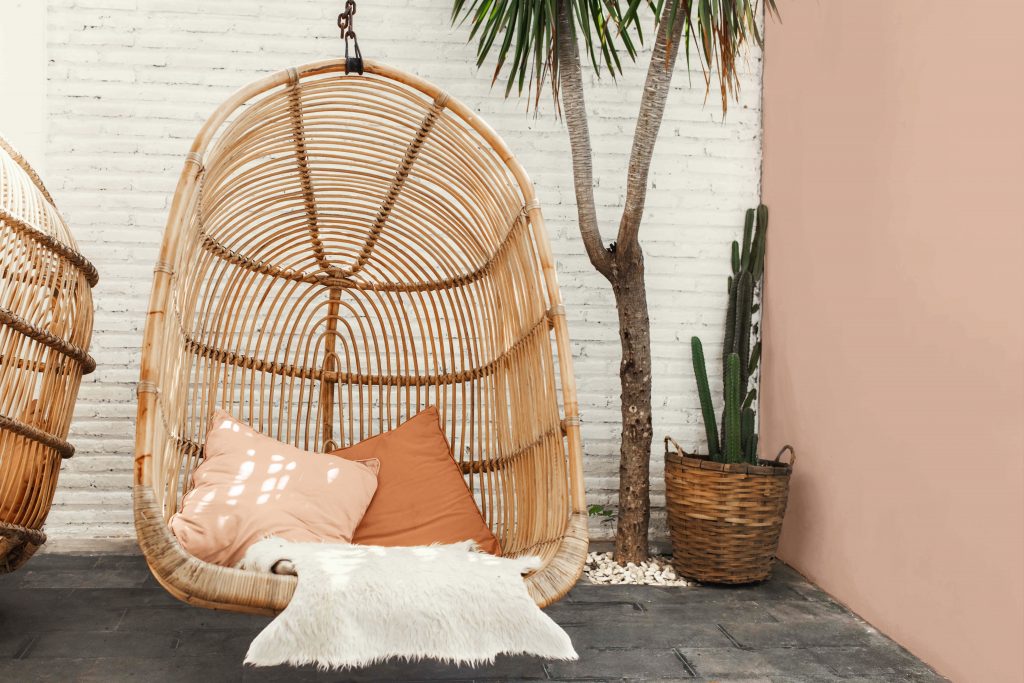 A natural bamboo swing sits against a warm clay-toned wall.