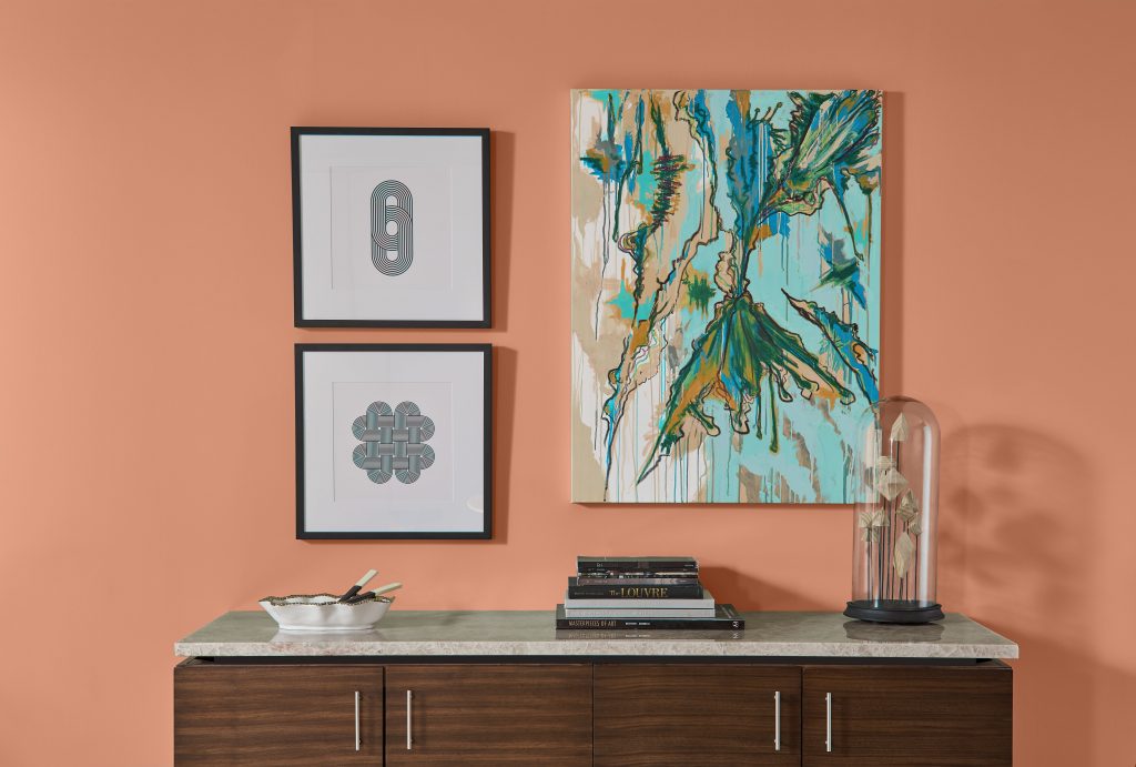Console table styled against a warm clay-colored wall with artwork above.
