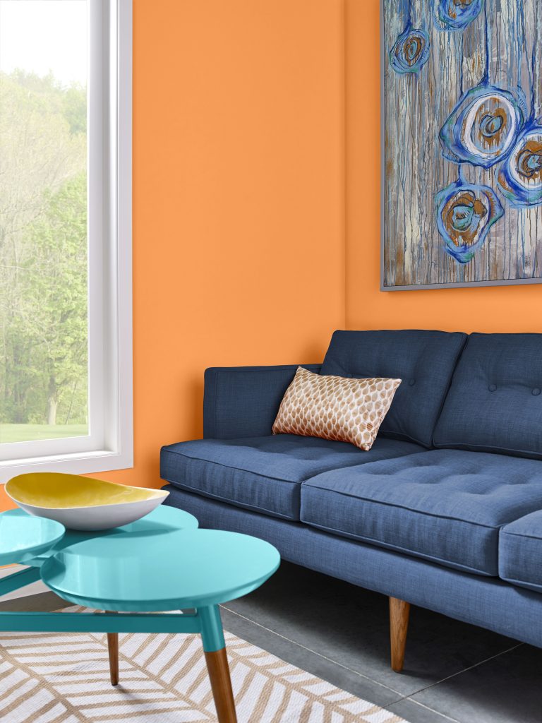 Living room with a bold orange accent wall and dark blue sofa.
